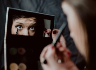Makeup Tricks That Make You Look Younger woman holding black framed mirror