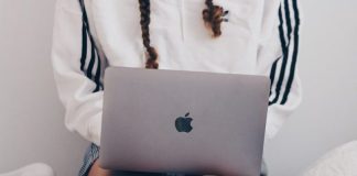 woman in white and black long sleeve shirt using silver macbook