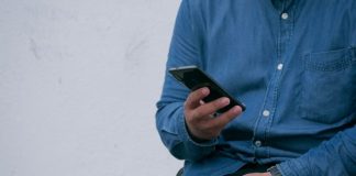 person in blue denim jacket holding smarthone