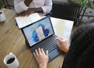 Benefits of Implementing Microsoft Dynamics 365 Overhead view of two people at a table working with a Microsoft laptop and notebook