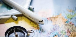 selective focus of miniature tourist on compass over map with plastic toy airplane,abstract background to travel concept.