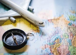 selective focus of miniature tourist on compass over map with plastic toy airplane,abstract background to travel concept.