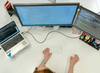 person using macbook pro on white table