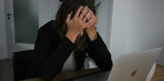 a woman covering her face while looking at a laptop