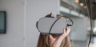 woman in black sweater holding white and black vr goggles