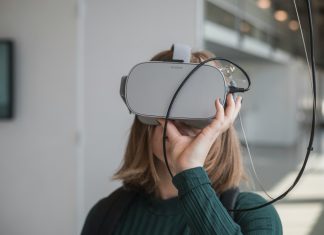 woman in black sweater holding white and black vr goggles