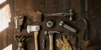 clothes iron, hammer, axe, flashlight and pitcher on brown wooden table