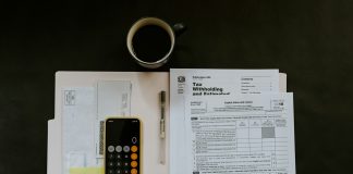 black Android smartphone near ballpoint pen, tax withholding certificate on top of white folder
