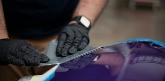 a man in black gloves waxing a blue car