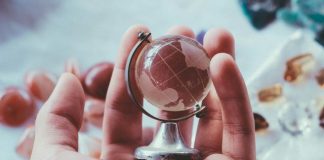 person holding gray metal framed desk globe paper weight