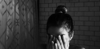 grayscale photo of woman covering her face with her hands