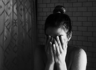 grayscale photo of woman covering her face with her hands