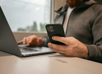 The Most Entertaining Ways to Bet Online in Georgia a man sitting in front of a laptop computer holding a cell phone