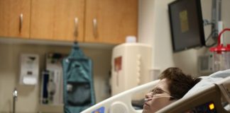 boy lying on beige recliner hospital bed