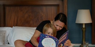 girl in red shirt lying on bed reading book