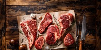 raw meat on a cutting board next to a knife