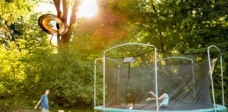 two children playing on a trampoline in a yard