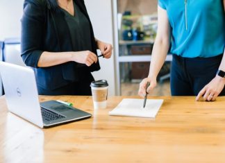 woman writing on paper on table near lapop