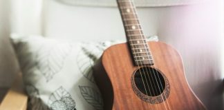selective focus photo of brown guitar on white pillow