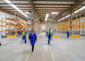 How a 3PL Warehouse Supports E-Commerce Growth Beyond the Startup Phase man in blue jacket and blue pants walking on yellow metal frame
