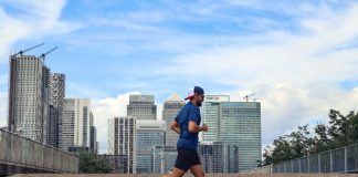 A man running in a city with tall buildings in the background