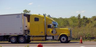 a yellow semi truck driving down a road