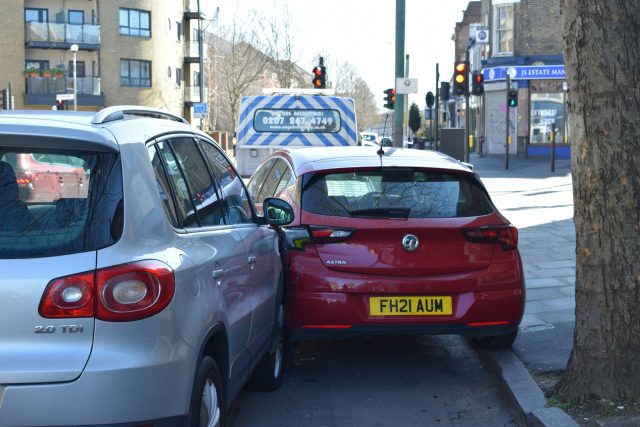 Photo by Usman Malik a red car is parked next to a silver car