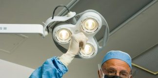 a man in a surgical gown holding up a surgical light
