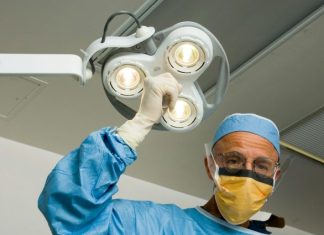 The Beauty of Caution: How to Pick the Right Plastic Surgeon a man in a surgical gown holding up a surgical light