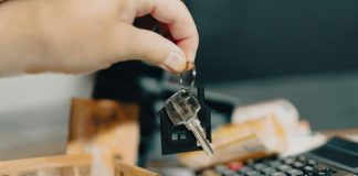 A person holding a house key in front of a calculator