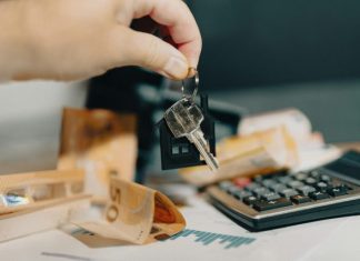 How Refinancing Your Home in Colorado Can Lower Your Monthly Payments A person holding a house key in front of a calculator