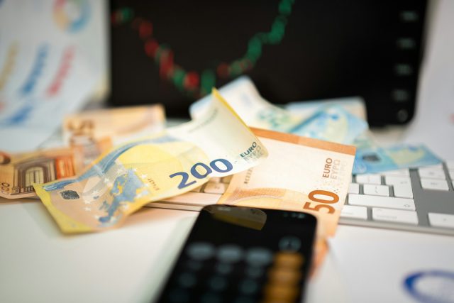 Photo by Jakub Żerdzicki A cell phone sitting on top of a pile of money