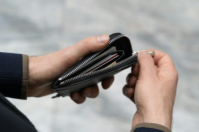 Photo by Aleksandrs Karevs a person holding a wallet in their hand