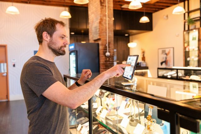 Photo by Cova Software a man standing in front of a display case holding a tablet
