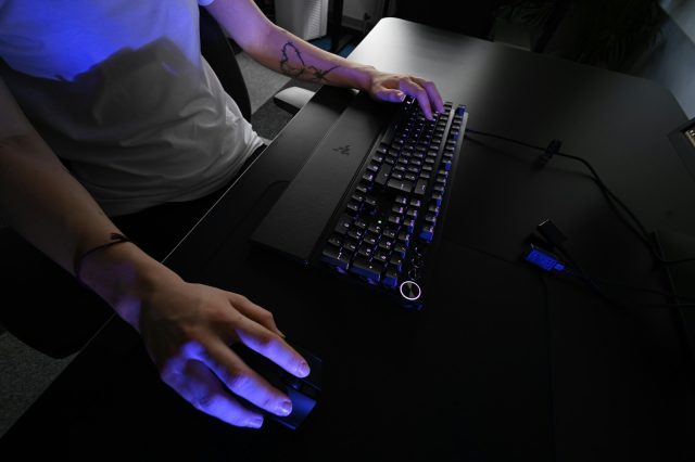Photo by ELLA DON A person sitting at a desk with a keyboard and mouse