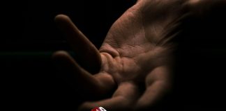a hand with a finger pointing at a red and white dice