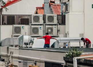 Why You Need Professional AC Repair Solutions To Stop Overpaying Energy Bills a couple of men standing on top of a roof