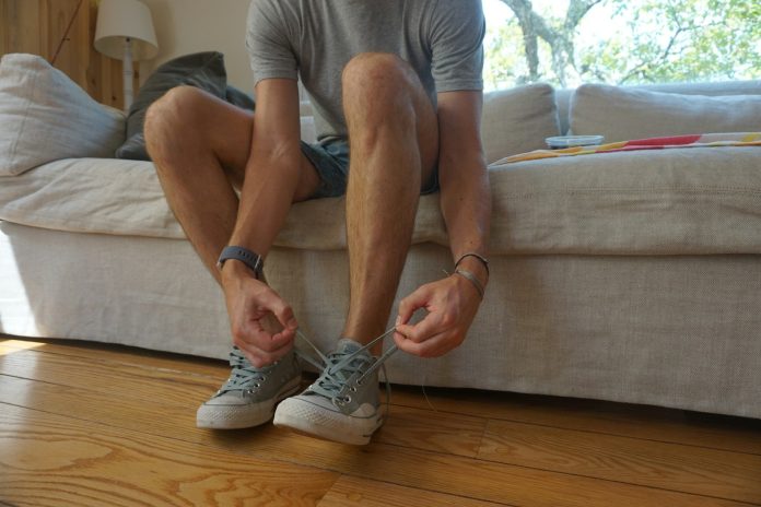 Photo by Adiel Gavish a man sitting on a couch holding his shoes