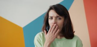 Woman covering mouth with hand, looking surprised.