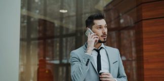 Man in suit talking on phone holding coffee cup