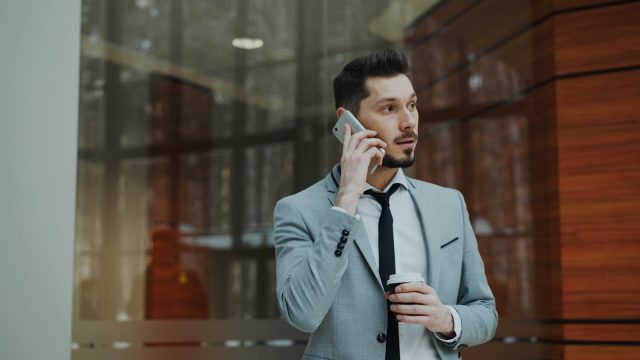 Photo by Vitaly Gariev Man in suit talking on phone holding coffee cup