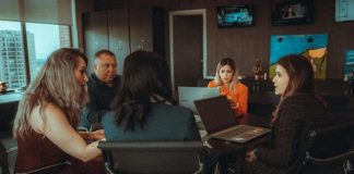 a group of people sitting at a table with laptops