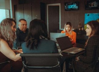 a group of people sitting at a table with laptops