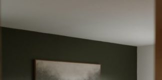 A modern bedroom with a tufted headboard and art.