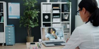 Doctor consulting patient via video call on laptop.