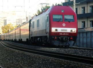 a red train traveling down train tracks next to a tall building