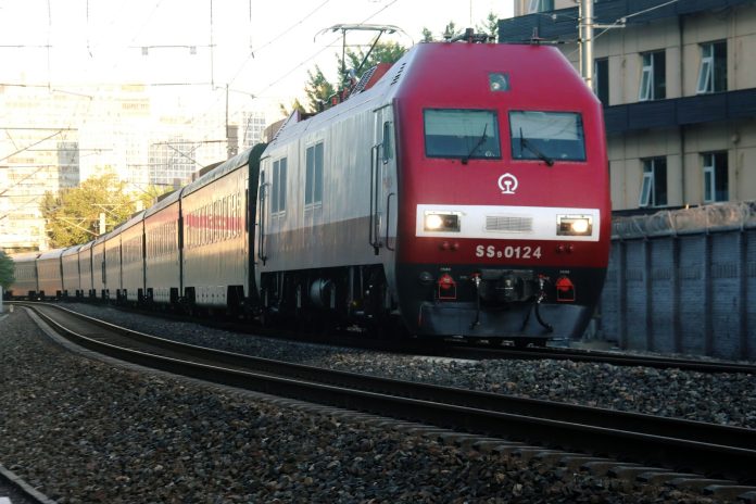 a red train traveling down train tracks next to a tall building