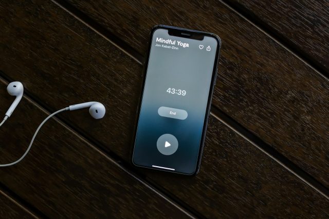 Photo by Mindfulness Com an iphone and ear buds on a wooden table