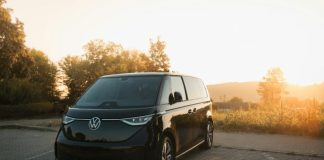 A black van driving down a road next to a forest