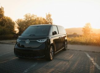 Evolving Travel Demands Influencing Motor Coach Rental Industry Innovation Trends A black van driving down a road next to a forest